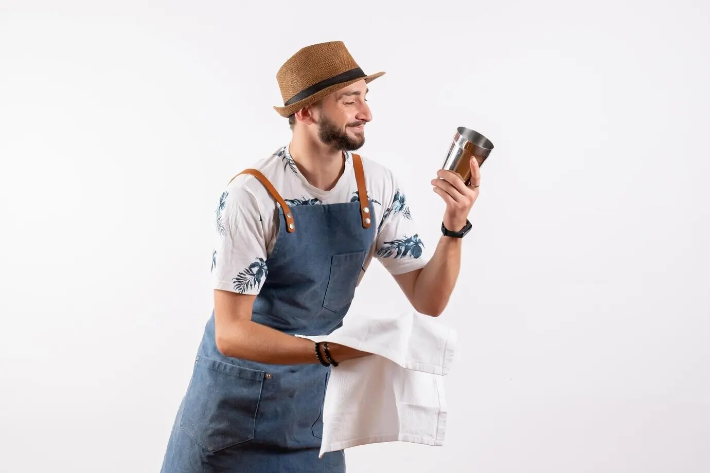 Vorderansicht eines männlichen Barkeepers, der vor einer weißen Wand einen Shaker reinigt; Clubnacht, alkoholische Getränke, Arbeit, in Farbe, Bar.