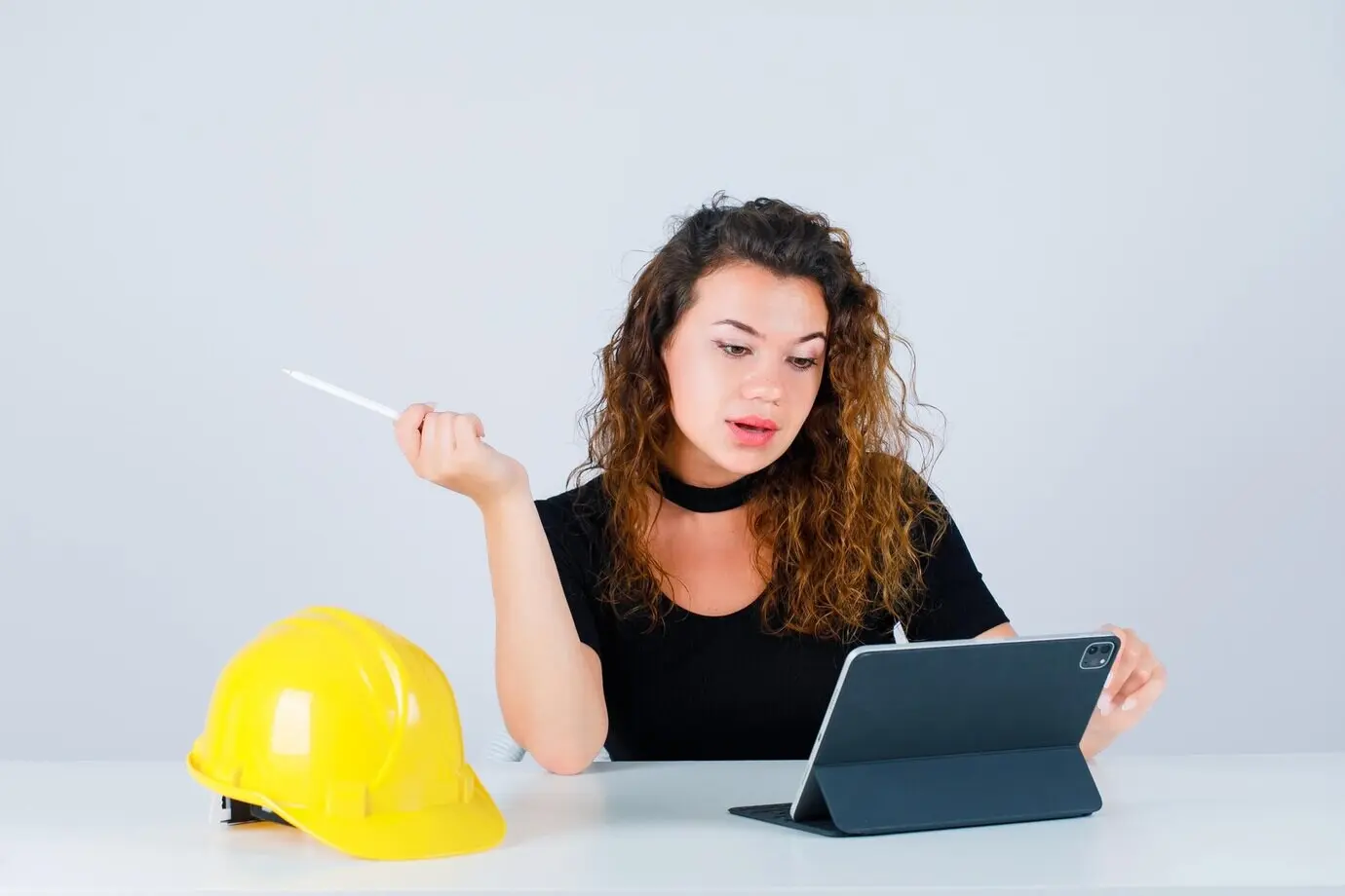 Eine junge Ingenieurin schaut auf ihr Tablet vor weißem Hintergrund.